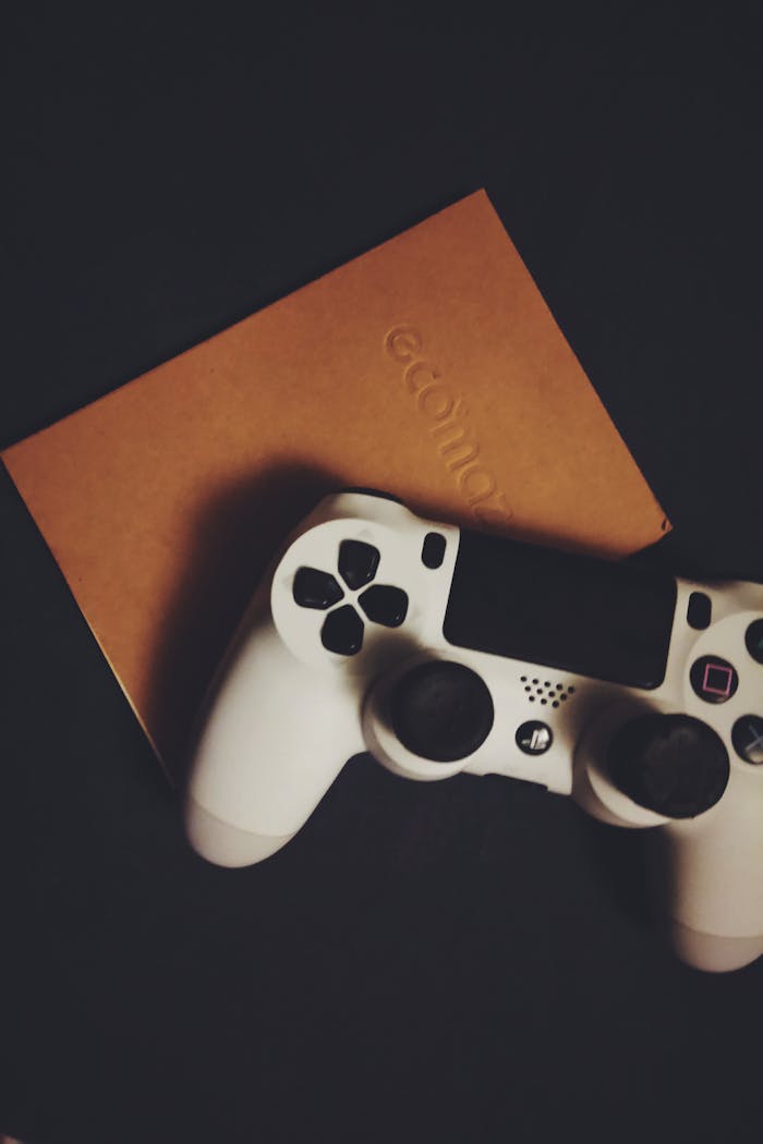 A white game controller rests on a brown notebook, offering a minimalist design.
